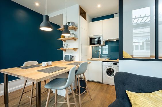 studio avec cuisine ouverte et mur peint en bleu petrole